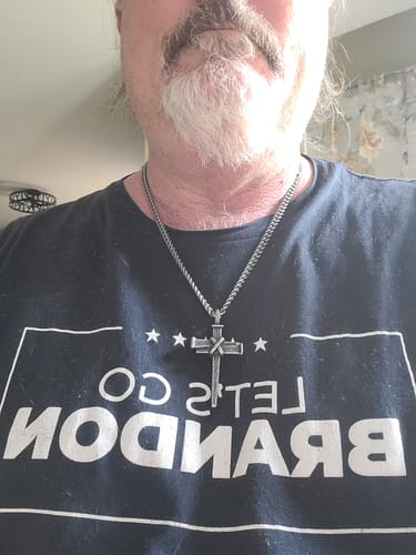 A customer wearing the antiqued Nailed to the Cross necklace over a dark t-shirt.