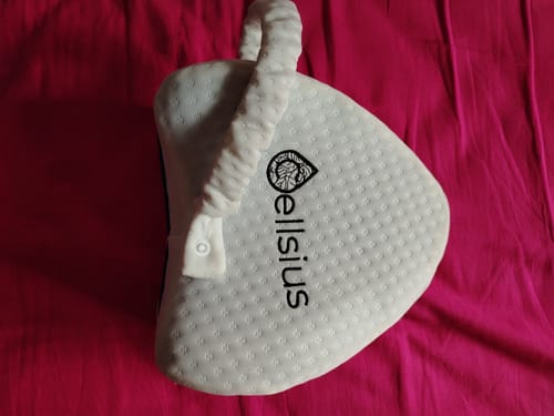 Le coussin orthopédique Cellsius d'un client, de couleur blanche et avec sa sangle, posé sur un drap rose.