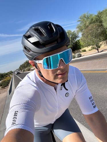 Customer wearing the white, short-sleeve LIFTTINT 1.X Jersey while cycling outdoors.