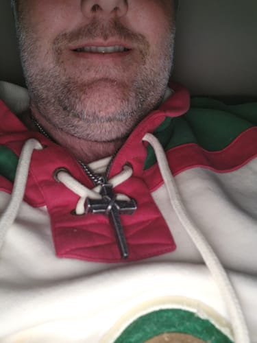 Close-up of a reviewer wearing the stainless steel Nailed to the Cross necklace against their hoodie.