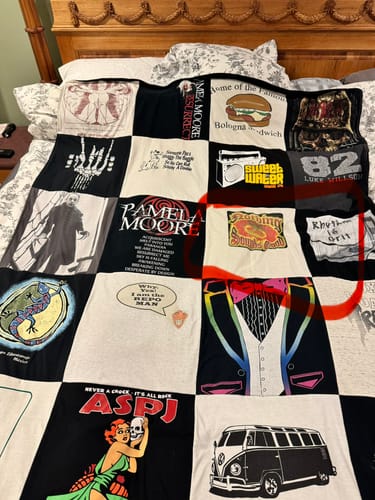 Close-up of a customer's Project Repat T-Shirt Quilt, showing various personal t-shirt squares sewn together on a bed.