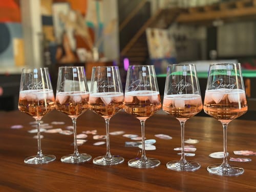Rezensent zeigt sechs gravierte Leonardo Weingläser 'Herzensmensch' mit Roséwein, aufgereiht für einen Junggesellinnenabschied.