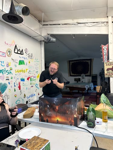 A reviewer acting as dungeon master, smiling and looking down at a die in his hands behind a game screen.