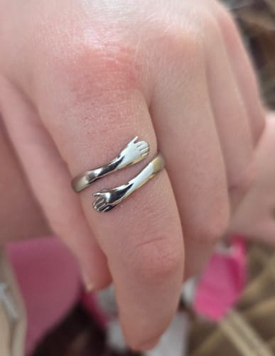 Close-up of a customer wearing the silver Hug Ring, designed as two arms wrapping around a finger.