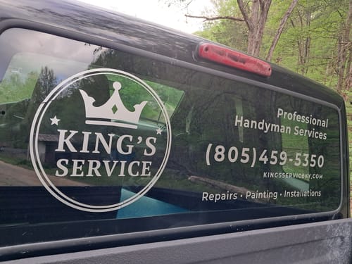 Customer's white custom vinyl decal displaying a business logo and text on the rear window of a truck.
