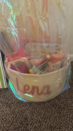 Customer's personalized woven basket with the name 'Lena', filled with gifts and wrapped in cellophane.
