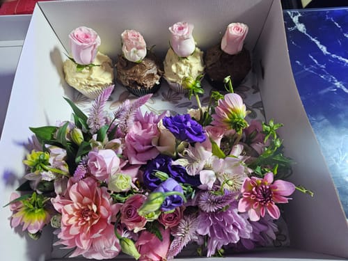 Customer's Cupcake Bloom Box with a lush floral arrangement and four cupcakes topped with fresh pink roses.