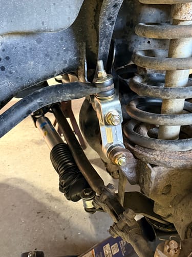 Customer's close-up of the new silver Sway Bar End Links Kit installed on a truck's suspension next to the coil spring.