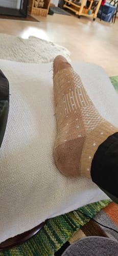 Recensent visar en fransig, beige Diasocks stödstrumpa på foten.