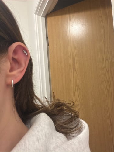 Customer's ear showing the silver Aurora Flatback Stud earring in their helix piercing.