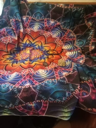 Customer's items from the AuraBloom Subscription Box, featuring a colorful mandala tapestry with several crystals placed on top.