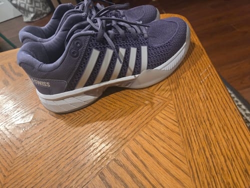 Reviewer's purple Express Light Pickleball shoes with white stripes on a wooden table.