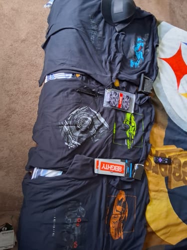 Reviewer's collection of multiple black 80Eighty graphic shirts and other merchandise laid out together.