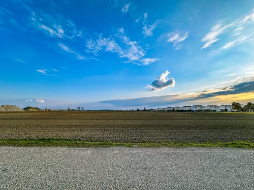 Reviewer's landscape photo edited with LANDSCAPE LIGHTROOM PRESETS, showing a field under a vibrant blue sky.