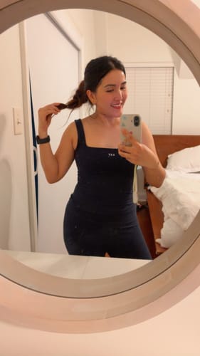Reviewer in a mirror selfie wearing the navy Square Tank, showing its square neckline and comfortable fit.