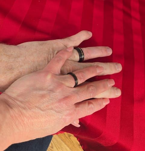 Customer review showing two hands wearing black Horizon rings. One ring has a rose gold groove.