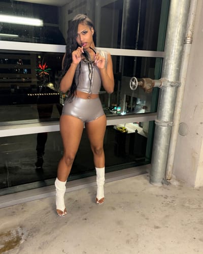 Reviewer standing indoors wearing the white Leather Socks scrunched down over heels with a silver outfit.