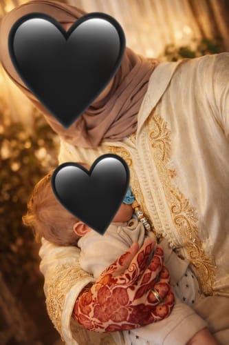 Close-up of a reviewer wearing the elegant Jellaba Rania, showing the detailed embroidery while holding a baby.