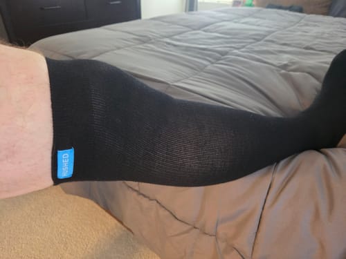 Close-up of a reviewer's leg wearing the black Performance Eucalyptus Compression Socks while resting.
