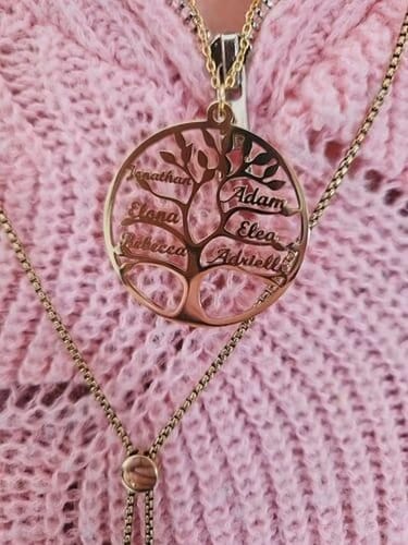 Kunde trägt die goldene Lebensbaum Kette mit Gravur vor einem rosa Strickpullover.