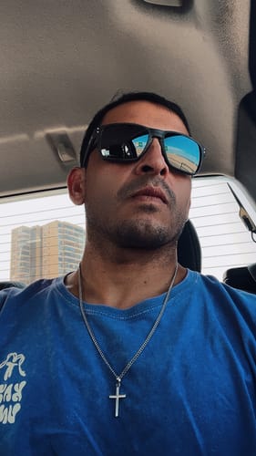Cliente luciendo su Cadena Miami Cuban con un dije de cruz sobre una camiseta azul.