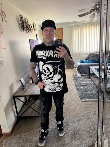 Reviewer taking a mirror selfie to show the fit of a black graphic t-shirt.