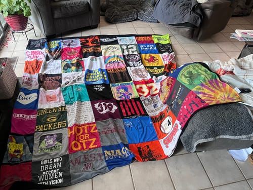 Customer's colorful Premium T Shirt Quilt made from many shirts, spread across a living room floor.