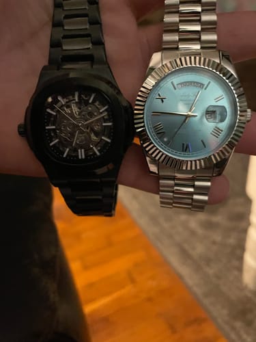 Customer holding a silver Lucky Fours® Santos watch with a blue dial and another black watch in their hand.