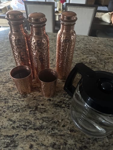 Customer's three Himalayan Ayurvedic Pure Copper Bottles and two cups on a counter next to a coffee pot.