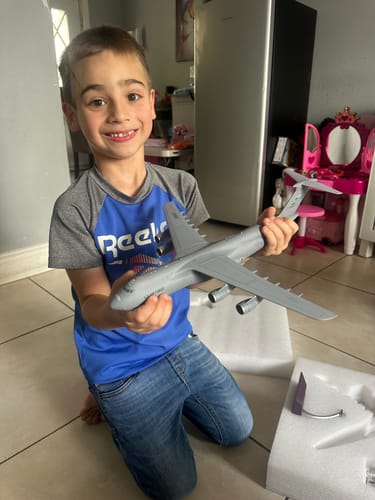 Reviewer's happy child holding the large, grey GEMINI200 USAF C5M model airplane indoors.