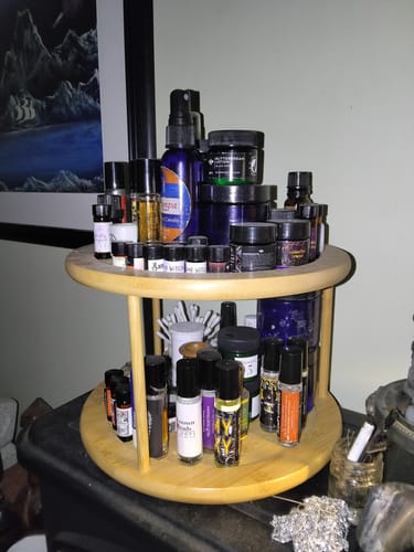 Reviewer's large collection of various perfume oils and jars, including Unknown Toads, on a two-tiered wooden stand.
