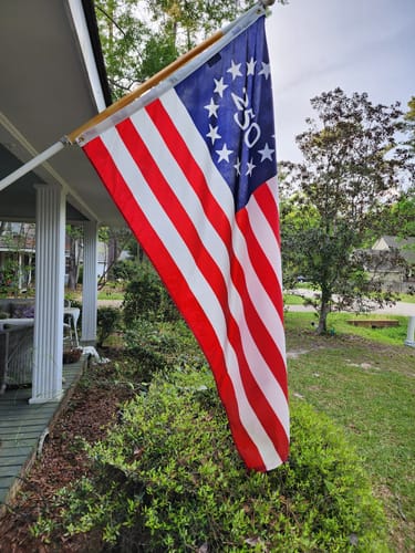 A customer's commemorative American flag with '250' in the star field, hanging from a pole on a porch.