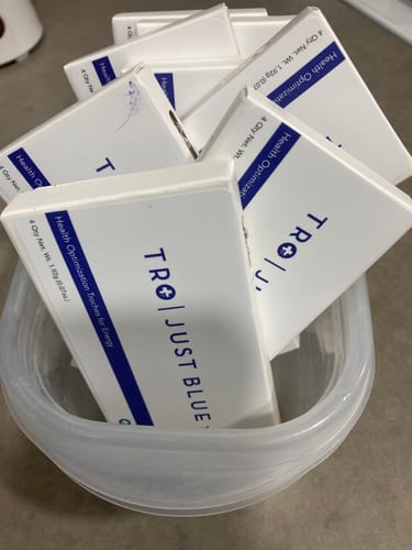 Customer's white boxes of Just Blue™ troches collected in a clear container.