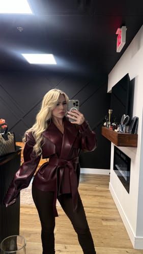Customer taking a mirror selfie wearing the burgundy Vegan Leather Cropped Trench Jacket with dark pants.