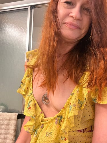 Customer in a yellow top showing her facial skin in a bathroom setting after her Professional Skin Scan.