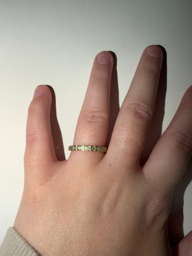 Customer's hand wearing the Eterna Birthstone Ring, showing the alternating yellow and light blue stones.