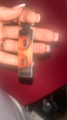 Ein Kunde hält den Kunstleder-Schlüsselanhänger mit dem bunten Augenmotiv in der Hand.