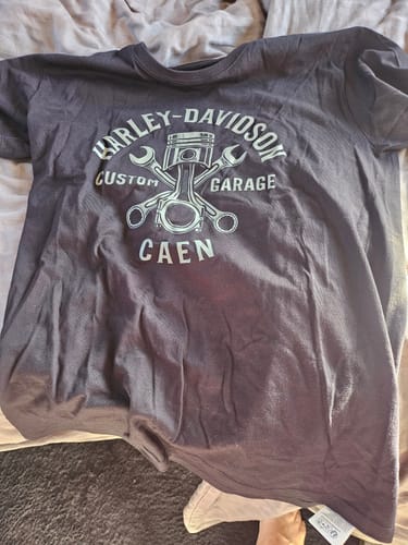 Avis du client : T-shirt Custom Garage gris foncé déplié. L'imprimé 'Harley-Davidson Custom Garage Caen' est visible sur le torse.