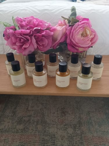 A customer's collection of fragrances, including Smooth Jazz, displayed on a wooden surface with flowers.