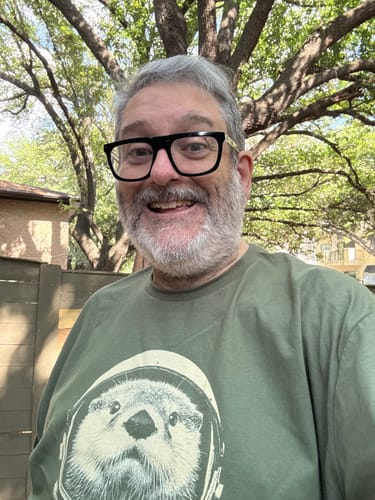 Customer smiling outdoors while wearing the green Otterspace t-shirt.