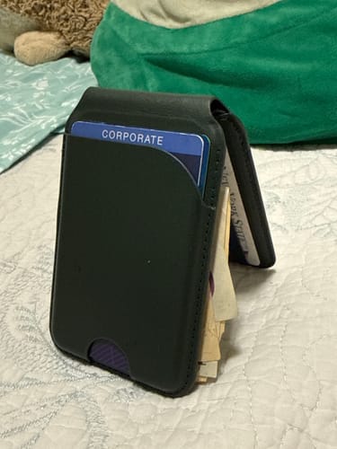 Customer's black MagWallet standing upright on a quilted surface, filled with cards and cash.