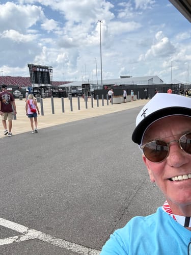 Reviewer taking a selfie wearing the white Faith Snapback hat at the Talladega Speedway.