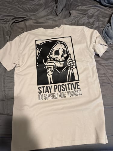 Reviewer's white Two Thumbs Up Tee laid flat, showing the back graphic of a skeleton giving two thumbs up.