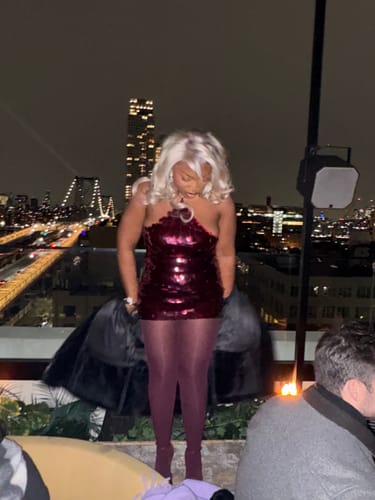 Reviewer on a rooftop at night, looking down at their cherry Sequin Open Back Halter Top.