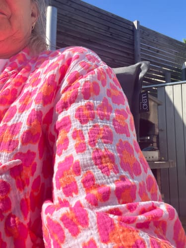 Nahaufnahme einer Kundin, die eine Bluse mit pinkem Leopardenmuster aus der Spring Surprise Box trägt.