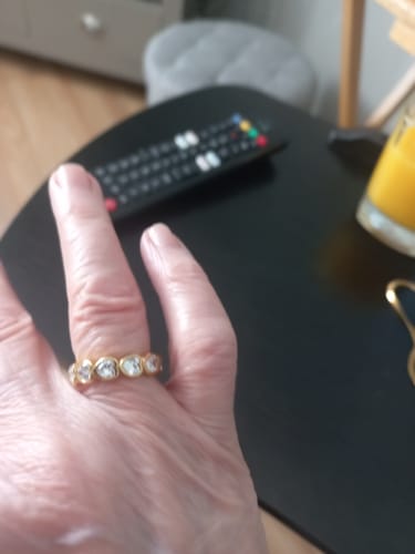 Customer's hand wearing a gold-colored ring with large clear stones.