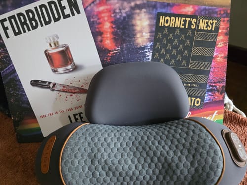 A customer's gray Thera Pillow, showing its textured surface, resting in front of some books.