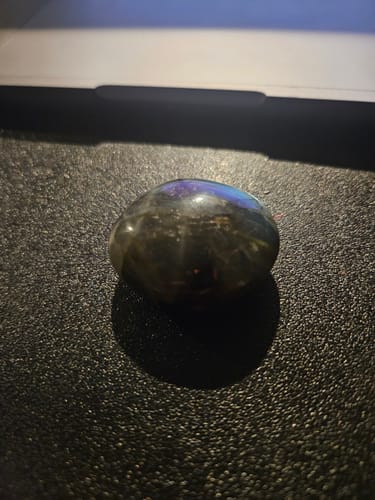 Customer's polished Labradorite Moonstone crystal showing an iridescent blue and purple flash on a dark surface.