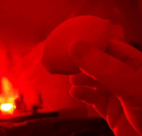 Customer holding the Lem Clitoral Massager in their hand, illuminated by strong red light.