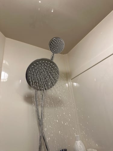 Customer's dual shower head installed, with the rain shower head spraying water with high pressure inside a shower.